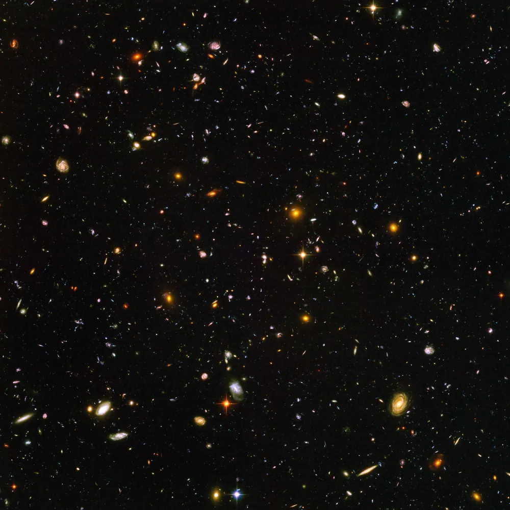 哈勃超深空场，方形画面中密布约一万个星系，许多只是暗红色的小点